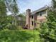 Brick home featuring a fireplace chimney, large windows, manicured lawn, and professional landscaping in a lush setting at 5775 Coopers Hawk Dr, Carmel, IN 46033