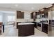 Open kitchen with dark cabinets, stainless steel appliances, a center island, and views into the living space at 5809 Terracotta Trce, McCordsville, IN 46055