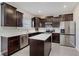 Open concept kitchen features dark cabinets, stainless steel appliances, an island, and quartz countertops at 5809 Terracotta Trce, McCordsville, IN 46055