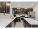 Well-lit kitchen features dark cabinets, stainless steel appliances, large island, and quartz countertops at 5809 Terracotta Trce, McCordsville, IN 46055