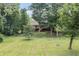 Expansive backyard with mature trees, a brick home featuring a large deck, and a fire pit area at 604 Oak Blvd W Dr, Greenfield, IN 46140