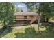 Brick home with a large deck and stairs leading to the expansive backyard surrounded by mature trees at 604 Oak Blvd W Dr, Greenfield, IN 46140