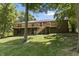 Spacious backyard featuring a brick home with a large deck, stairs, and mature trees at 604 Oak Blvd W Dr, Greenfield, IN 46140
