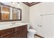 Bathroom featuring wallpaper, dark wood cabinetry, and a shower reflected in the mirror at 604 Oak Blvd W Dr, Greenfield, IN 46140