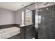 Modern bathroom featuring a sleek glass-enclosed shower, a soaking tub, and stylish gray tile work at 7865 Danube St, Indianapolis, IN 46239