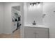 Modern bathroom featuring white vanity, matte black fixtures, and a door leading to the kitchen at 10222 Arapahoe Dr, Indianapolis, IN 46235