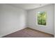 A light-filled bedroom features neutral walls, carpet flooring, and large window with lush, green outdoor view at 10222 Arapahoe Dr, Indianapolis, IN 46235