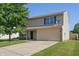 Two-story home featuring a tan facade, green shutters, a two-car garage and mature landscaping at 10222 Arapahoe Dr, Indianapolis, IN 46235