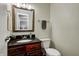Charming powder room with a dark wood vanity, granite countertop, and decorative mirror, offering a touch of elegance at 1106 Barbara Dr, Greenwood, IN 46143