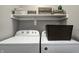 Well-organized laundry room with white washer and dryer, a storage shelf, and decorative baskets for a practical space at 1106 Barbara Dr, Greenwood, IN 46143