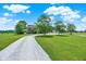 Scenic view of a house featuring a long driveway, spacious lawn, and mature trees under a bright sky at 11250 N 600 W, Fountaintown, IN 46130
