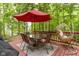Backyard deck with dining table, umbrella and swing chair, surrounded by lush greenery at 12214 Ridgeside Rd, Indianapolis, IN 46256