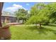 Inviting backyard featuring a brick pathway, lush green lawn, mature trees, and a wood back deck at 12222 Cable Dr, Indianapolis, IN 46236