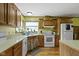 A kitchen with natural wood cabinets and a white electric range stove with a window above the sink at 12222 Cable Dr, Indianapolis, IN 46236