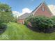 View of the side of the home with manicured lawn and garden bed at 13221 Griffin Run, Carmel, IN 46033