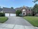 Traditional brick home features a well-manicured lawn, three-car garage and a long curved driveway at 13221 Griffin Run, Carmel, IN 46033