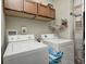 Functional laundry room with modern washer and dryer units and wood cabinets at 1331 Mccormicks Cir, Danville, IN 46122