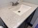 Close-up of the bathroom sink with a stone-look countertop and dark wood cabinets beneath at 1433 N Colorado Ave, Indianapolis, IN 46201