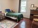 A comfortable bedroom with hardwood floors, area rug, and a bed with a patterned green coverlet at 1433 N Colorado Ave, Indianapolis, IN 46201