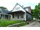 Side view of a two-story home needing renovation with front porch and adjacent overgrown landscaping at 1601 Spann Ave, Indianapolis, IN 46203