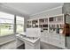 Bright home office features custom built-ins, a large window, and sleek white adjustable height desk at 17390 Tribute Row, Noblesville, IN 46060