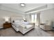 Spacious primary bedroom featuring a tray ceiling, neutral decor, and an accent chair at 17390 Tribute Row, Noblesville, IN 46060