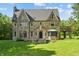 Stately stone home with arched entry, bay window and attached covered patio overlooking manicured front lawn at 2421 W 39Th St, Indianapolis, IN 46228