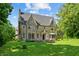 Two story stone home with chimney, arched doorway, bay window, and covered patio on a landscaped lawn at 2421 W 39Th St, Indianapolis, IN 46228