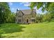 Stone home with peaked roof, arched doorway, bay window, and covered patio on a well manicured front lawn at 2421 W 39Th St, Indianapolis, IN 46228