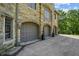 Attached three-car garage with arched entryways featuring mature landscaping and sconce lighting at 2421 W 39Th St, Indianapolis, IN 46228