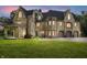Stone home with arched entry to covered patio, attached garage, and illuminated windows at dusk at 2421 W 39Th St, Indianapolis, IN 46228