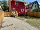 View of the fenced backyard, and side entry with stairs on the back of the red house at 2423 E 13Th St, Indianapolis, IN 46201