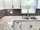 Bright kitchen featuring granite countertops, stainless steel sink, and a subway tile backsplash at 2423 E 13Th St, Indianapolis, IN 46201