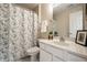 Well-lit bathroom with a floral shower curtain, white vanity, and a framed picture for décor at 246 Legends Creek Way # Apt 207, Indianapolis, IN 46229