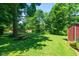 Expansive backyard with lush green lawn, mature trees, picnic table, and a storage shed at 2808 Woodside Dr, Plainfield, IN 46168