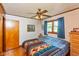 Comfortable bedroom with ceiling fan, hardwood trim, and three windows with blue curtains with wood flooring at 2808 Woodside Dr, Plainfield, IN 46168
