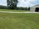 Beautifully maintained backyard with a long driveway, storage building, and lush green grass, perfect for outdoor activities at 3310 W State Road 58, Seymour, IN 47274