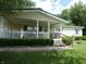 Inviting home exterior with a cozy porch and white picket fence, nestled in a well-manicured yard with green grass at 3310 W State Road 58, Seymour, IN 47274