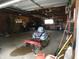 A wide-open garage with overhead storage and a riding lawn mower inside at 3310 W State Road 58, Seymour, IN 47274