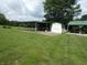 Green lawn featuring sheds and an open structure with metal roofs, offering storage and covered space at 3310 W State Road 58, Seymour, IN 47274