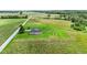 Wide aerial view of tan home with American flag, shed, and playset, nestled among fields and trees at 3450 Clay Rd, North Salem, IN 46165