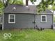 View of home's backyard with grey siding, a grassy yard, and trees providing shade at 4405 Primrose Ave, Indianapolis, IN 46205