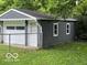 View of detached garage with roll up door and gray siding surrounded by grass at 4405 Primrose Ave, Indianapolis, IN 46205