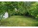 Wide backyard featuring green grass, mature trees, and a detached garage, perfect for outdoor activities at 4517 E 16Th St, Indianapolis, IN 46201