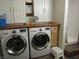 A well lit laundry room featuring front load washer and dryer, wooden countertops, and white cabinetry at 4521 Tulip N Dr, Martinsville, IN 46151