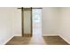 Bright bedroom features a sliding barn door, wood-look floors, and a window at 5115 Primrose Ave, Indianapolis, IN 46205
