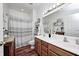 Well-lit bathroom featuring a double sink vanity, a shower with curtain, and decorative shelves at 5217 Dunewood Way # 3002, Avon, IN 46123