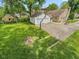 An aerial view shows the stone home, garage, long driveway, mature trees, and lush lawn at 6030 Evanston Ave, Indianapolis, IN 46220
