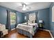 Spacious bedroom showcasing hardwood floors, blue walls, and bright windows at 6030 Evanston Ave, Indianapolis, IN 46220