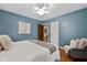 Large bedroom showing hardwood floors, blue walls, and a ceiling fan at 6030 Evanston Ave, Indianapolis, IN 46220